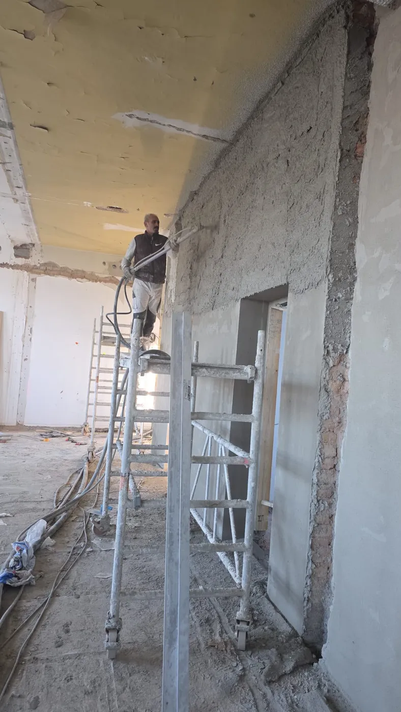 Maschineller Auftrag von Kalkzementputz auf eine Innenwand durch DD21BAU