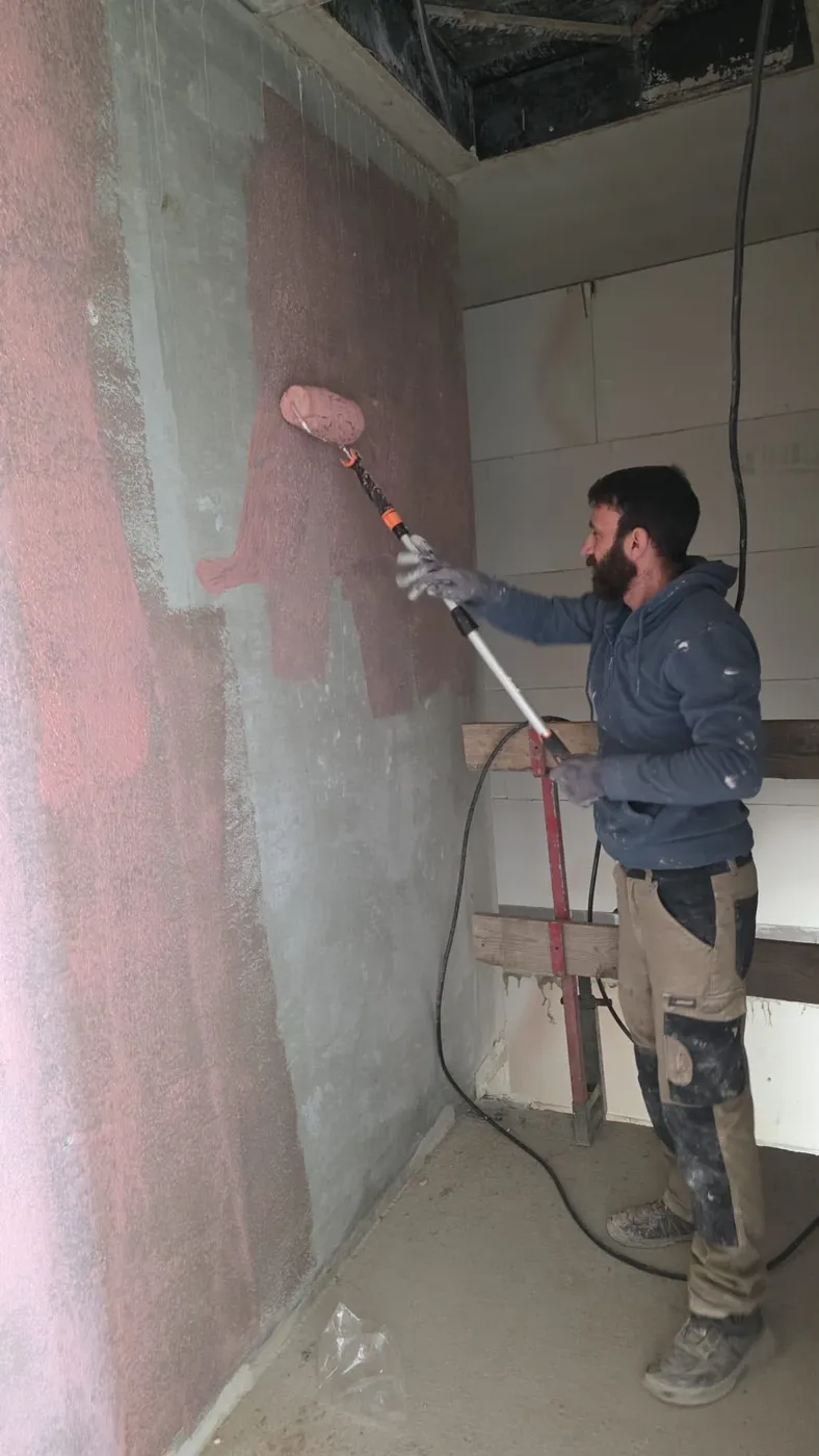 Auftragen von Putz auf eine Wandfläche im Rohbau